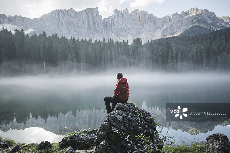 瑞士，黎明时分，一个年轻人坐在白云石阿尔卑斯山脉的卡里扎湖图片素材