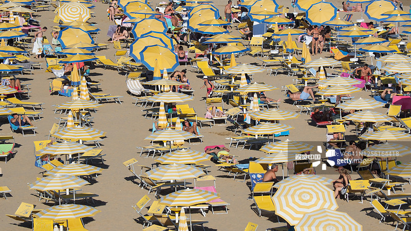 Jesolo,意大利。意大利沙滩上的沙滩伞和日光浴床。旺季，很多人又很多乱。亚得里亚海海岸。黄白伞图片素材