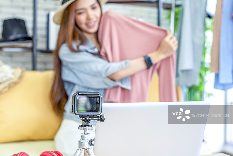 美丽的亚洲女人博客展示和评论产品。在摄像机前录制在家的视频直播。商业在线影响者对社交媒体的概念。图片素材