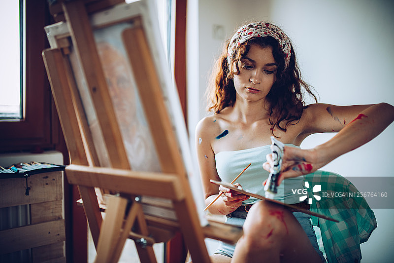 美丽的年轻女艺术家在她的艺术工作室绘画图片素材