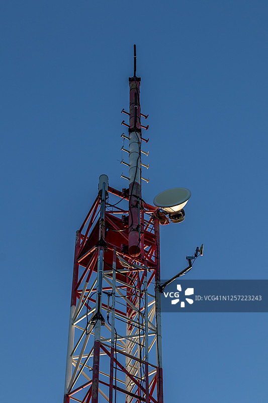 一个广播塔的特写，充满了设备，背景是蓝天。图片素材