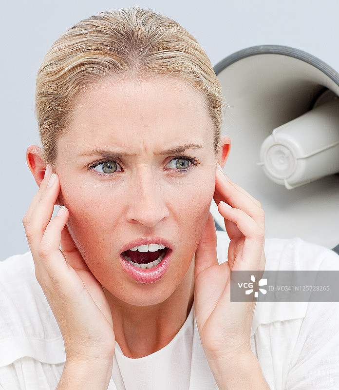 一个人用扩音器对着一个女人的耳朵大喊大叫的肖像图片素材