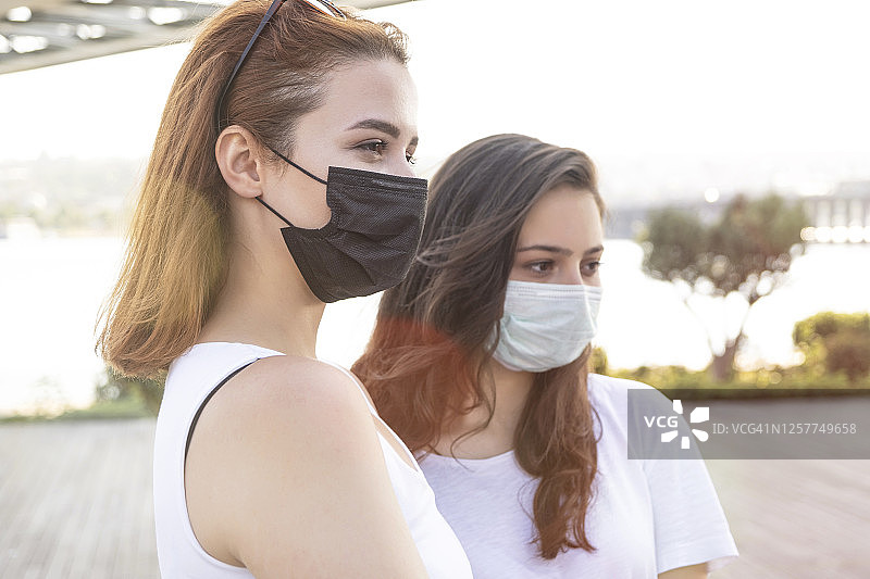 2019年新冠肺炎大流行的冠状病毒，在城市街道上的年轻女孩戴着口罩，以防止冠状病毒疾病的传播。近距离观察戴着防护口罩的年轻妇女，以预防SARS-CoV-2。图片素材