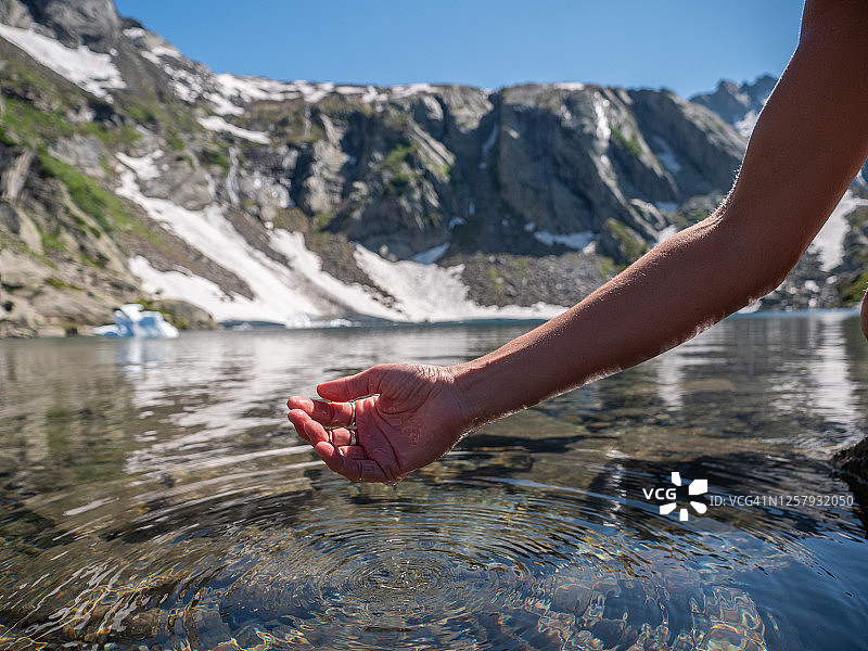 手从高山湖舀水图片素材