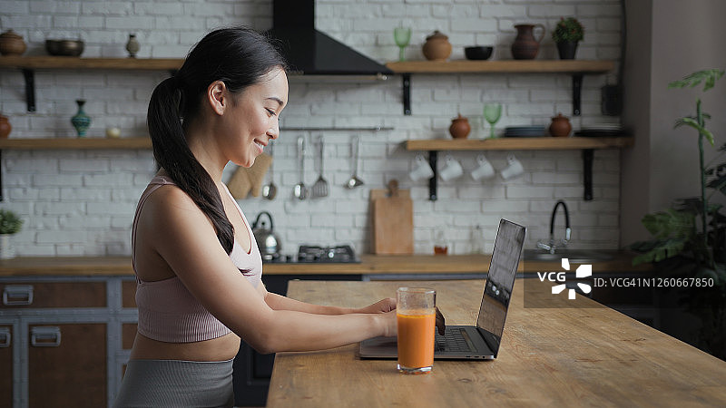健康的亚洲女性使用笔记本电脑，发短信，喝新鲜果汁图片素材