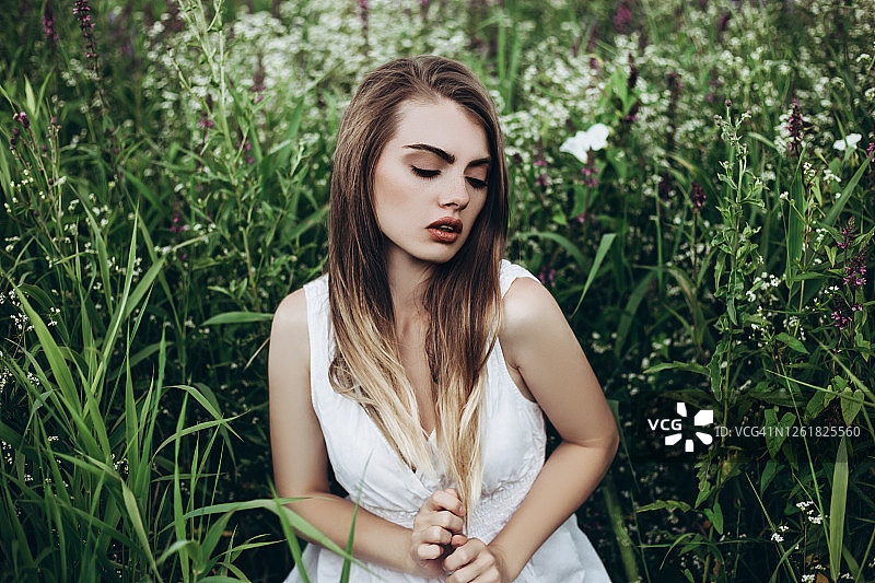 穿着白衣的年轻美丽女子坐在花丛中图片素材