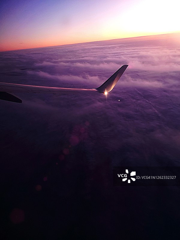 黎明前的飞机鸟瞰图，有紫外线色调和浓密的云层覆盖着地球图片素材