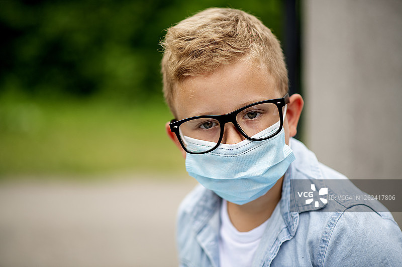 一名男孩戴着口罩上学，以避免冠状病毒的传播图片素材