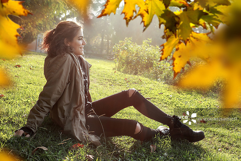 美丽的年轻女子坐在绿色的草地景观图片素材