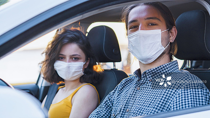肖像司机戴着防护医用口罩，年轻的朋友在车里微笑图片素材