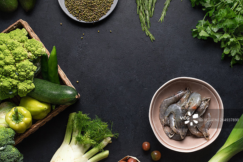 绿色蔬菜和虾，食物背景。健康饮食理念的黑餐桌上的新鲜有机产品图片素材
