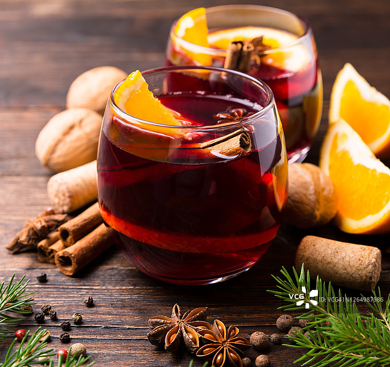 两杯热红酒加橘子和香料，木质背景上点缀着冬天的装饰。冬天和秋天的热饮。秋冬静物生。图片素材