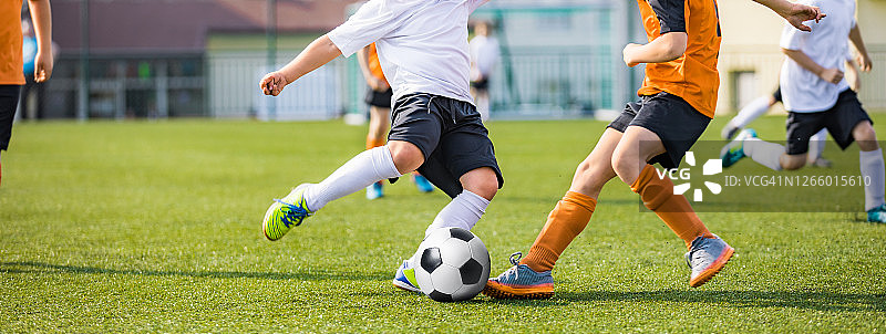 孩子们在足球场上踢球。体育足球水平背景。背景是体育场的观众。穿着红色和蓝色足球衫的青少年运动员。体育教育图片素材