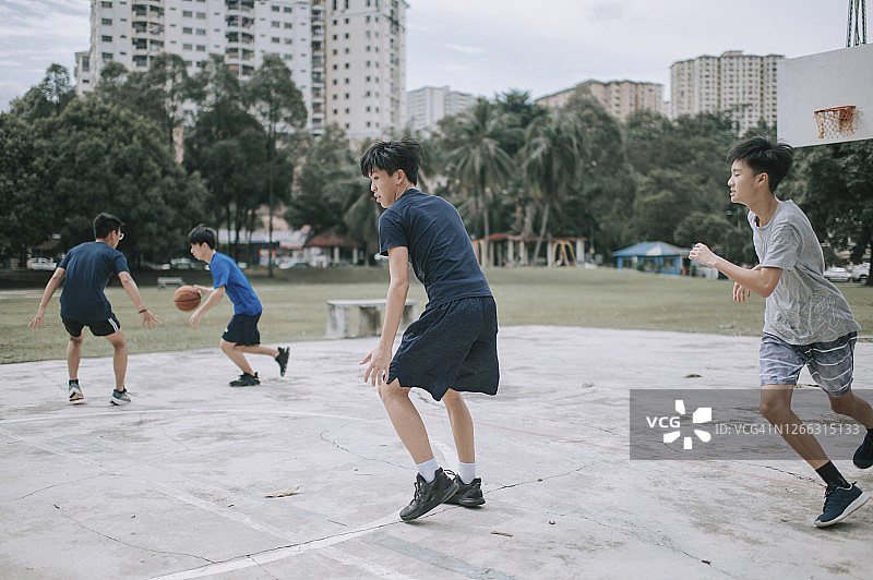 一群十几岁的亚裔中国男孩放学后在篮球场上打篮球图片素材