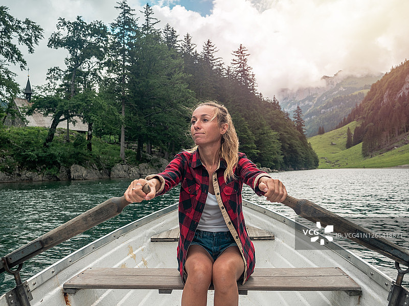 在高山湖上划船的金发女人图片素材