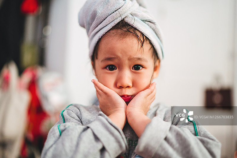 可爱的小女孩用发巾包在家里的相机前做鬼脸图片素材