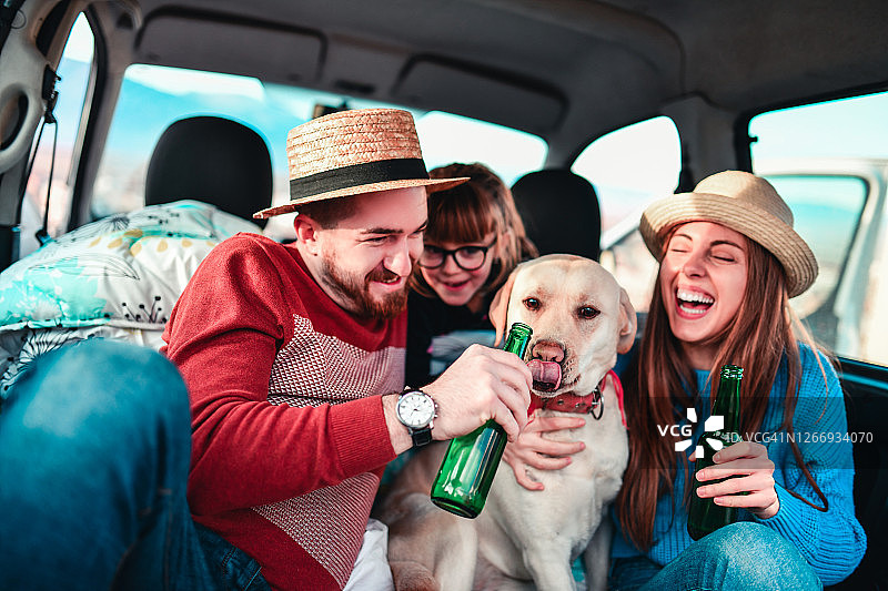 快乐的家庭享受公路旅行与狗和啤酒的乐趣图片素材
