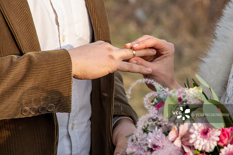 特写新娘的手把戒指戴在男人的手上。外注册。定制的婚礼图片素材