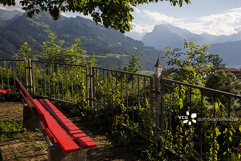 红色长凳，可以看到绿色的自然和山脉图片素材