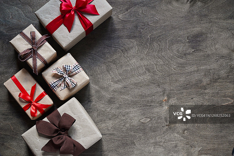许多礼品盒用牛皮纸包裹，用不同的丝带绑在木制的背景上，俯视图，拷贝空间。圣诞节和新年的概念。图片素材