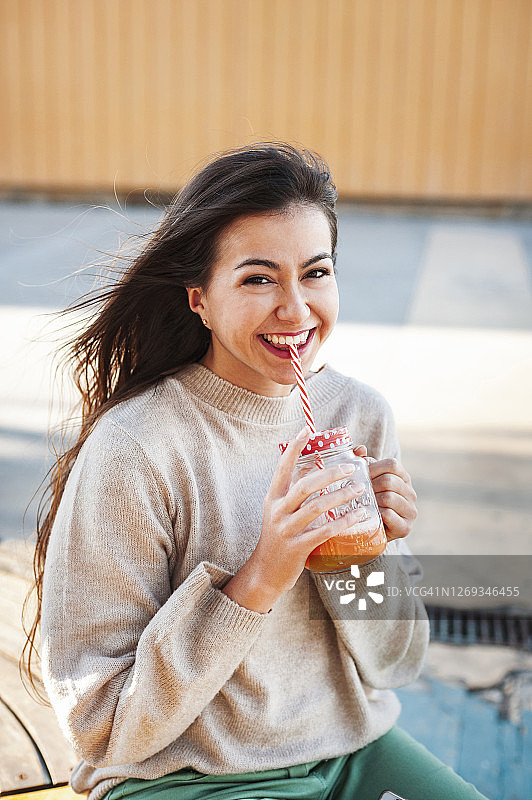 愉快的年轻女子与长棕色的持有饮料图片素材