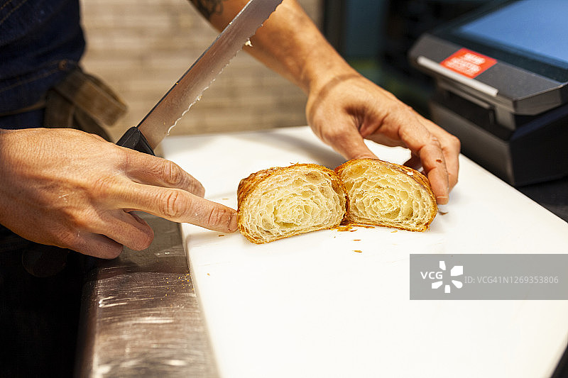 面包师在面包店的厨房柜台上切面包图片素材