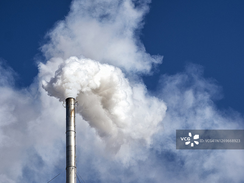 工业工厂的烟囱向大气中排放烟雾和气体污染。图片素材