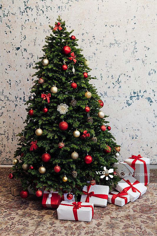 白色房间的内部是一棵绿色的圣诞树，上面挂着红色的礼物，作为新年假期的装饰图片素材