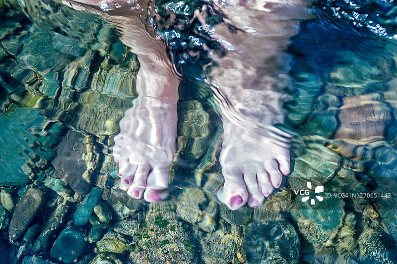 脚在水下的石头下的女人的光脚。水中自拍，俯视图图片素材