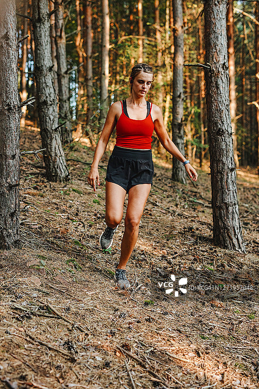 运动活跃的女人跑下坡的岩石小径在山区地形图片素材