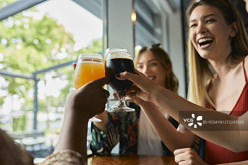 快乐的女性朋友在酒吧里碰杯手工啤酒杯图片素材