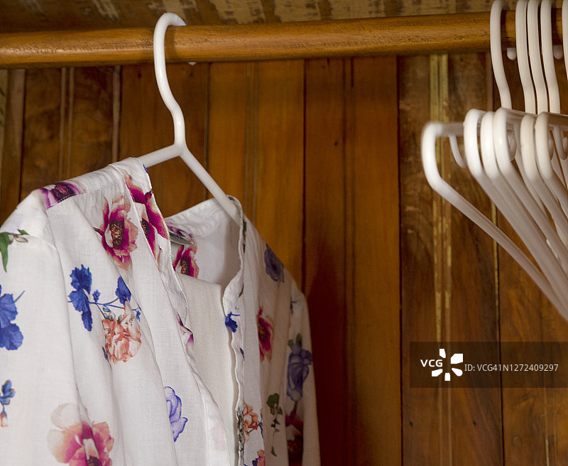 一个木制的柜子里摆着一件带有花卉图案的白衬衫。图片素材