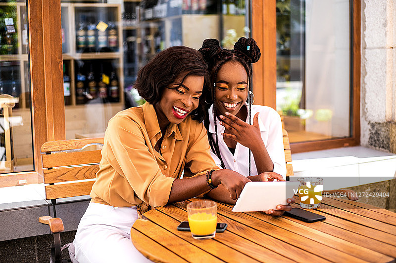 两个漂亮的黑人女孩在街上的咖啡馆一起玩。图片素材