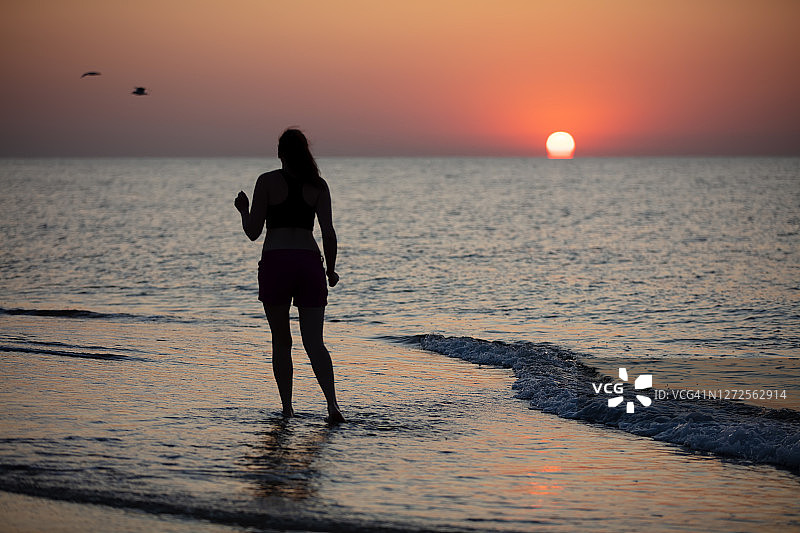 一个女运动员的剪影在海上日出的背景上图片素材