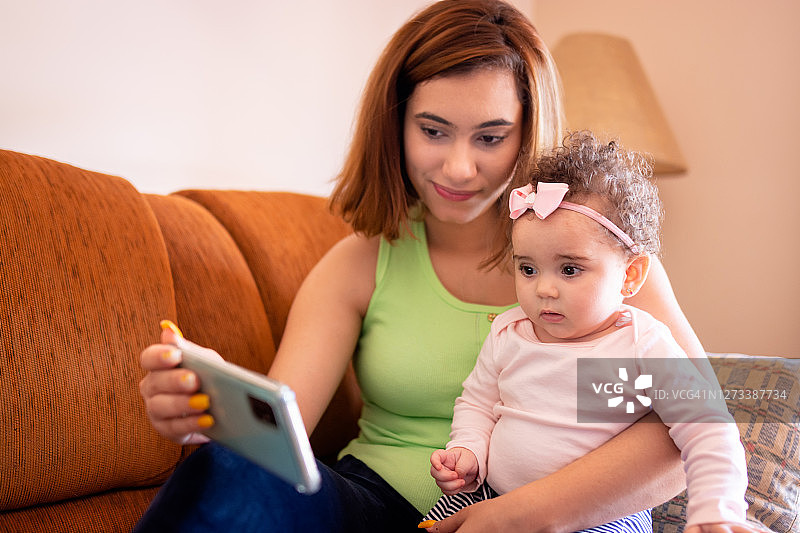 妈妈和她的宝贝女儿在沙发上玩手机图片素材