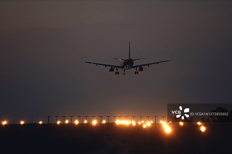 一架商用飞机在日落时接近跑道准备着陆图片素材