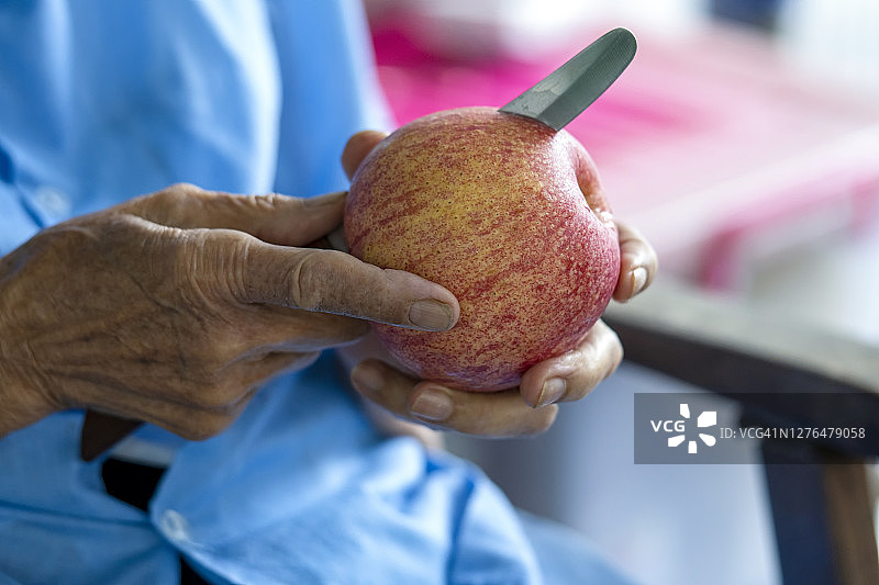 老人的手正在切苹果。图片素材