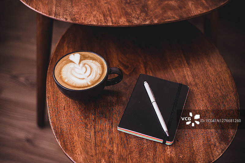 咖啡拿铁，怪兽植物和笔记本放在木桌上图片素材