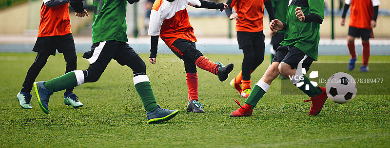 学校男生在踢足球。年轻球员在草地上踢足球。快乐的孩子们在操场上比赛图片素材