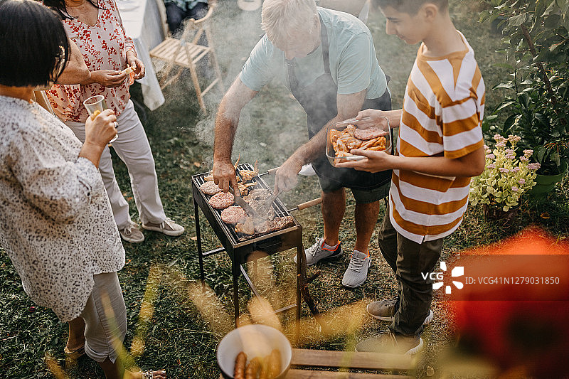 在家庭聚会上，老人直接从烧烤上提供食物图片素材
