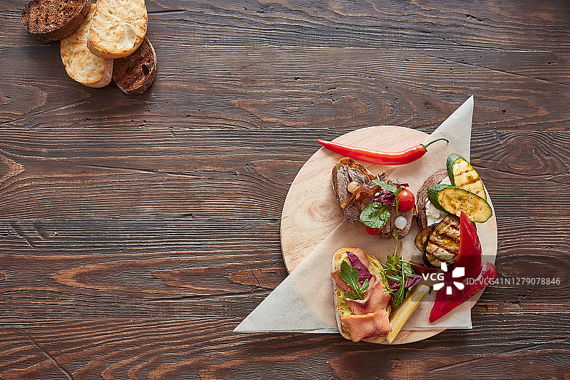 意式烤面包配鱼、肉、蔬菜和奶酪放在木板上。传统的意大利开胃菜或开胃菜，开胃菜图片素材