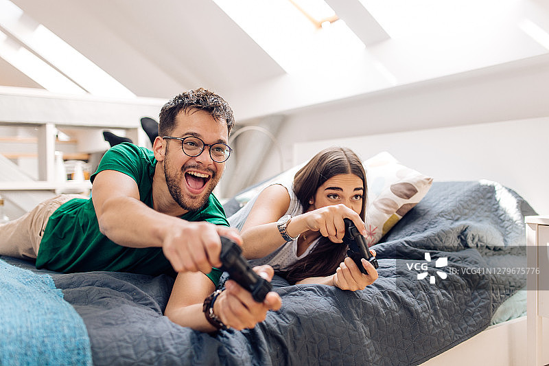 年轻夫妇在家里玩电子游戏，玩得很开心图片素材
