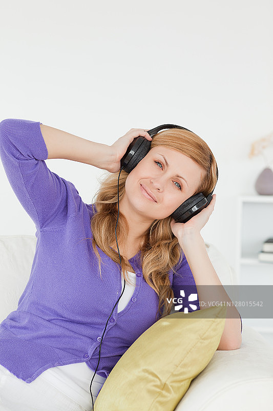 漂亮的红发女人坐在沙发上听音乐，享受此刻图片素材