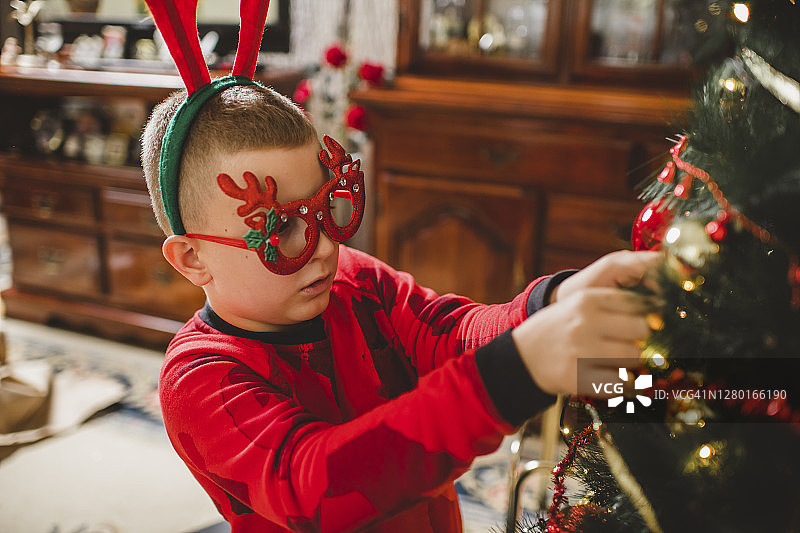白人男孩在家里装饰圣诞树图片素材
