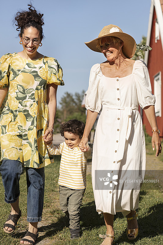 蹒跚学步的小男孩与母亲和祖母走在一起图片素材