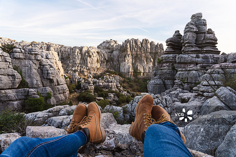 一对年轻游客的腿在一个被侵蚀的喀斯特岩石景观图片素材