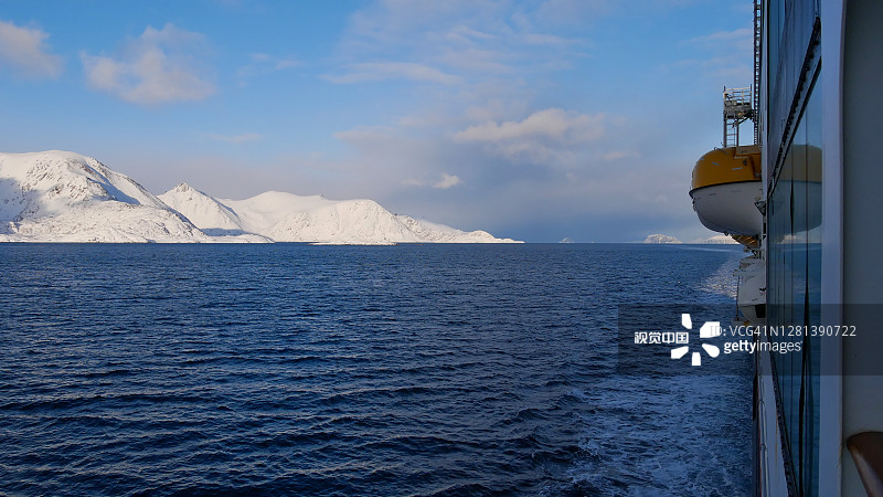 海达gruten游轮MS Trollfjord在冬天通过北冰洋上的索罗亚岛附近的一个海峡，那里的山脉被白雪覆盖。图片素材
