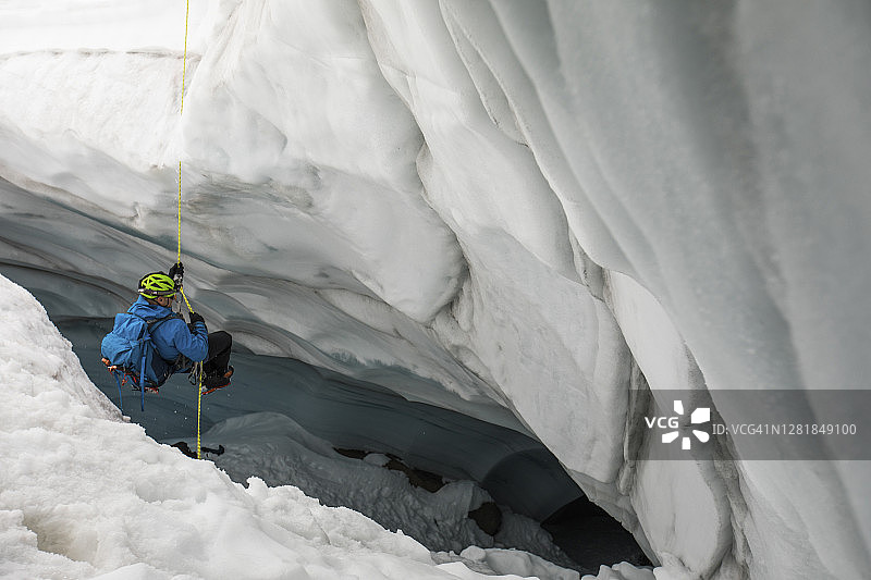 登山者滑降到冰川裂缝中探索洞穴。图片素材