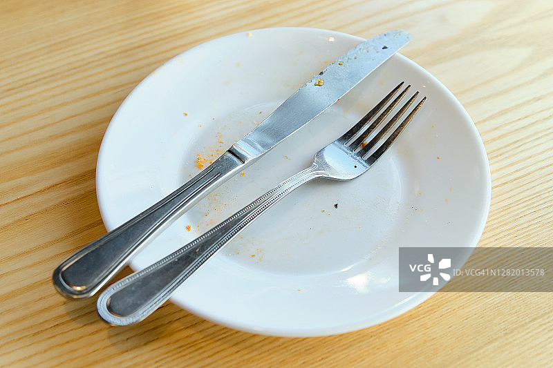 脏盘子、叉子和刀放在木桌上。使用过的餐具，象征着午餐或晚餐的结束。图片素材