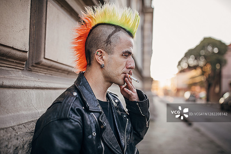 一个留着五颜六色发型的流氓站在街上抽烟图片素材